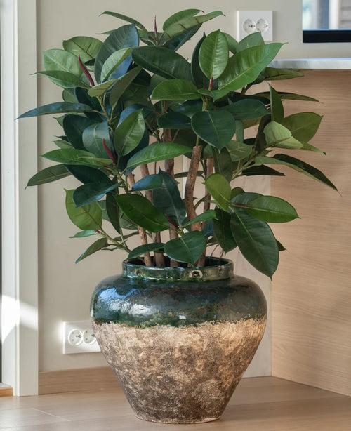 La planta artificial Rubber deluxe de 90 cm tiene hojas anchas y de color verde brillante y se presenta en una gran maceta rústica de cerámica, ideal para quienes aman el aspecto de las plantas de caucho sin necesidad de mantenimiento.
