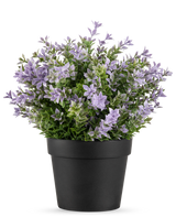 La Planta Artificial Buxus violeta UV 22 cm tiene una maceta negra con una exuberante planta artificial con pequeñas flores de color violeta claro y hojas verdes sobre un fondo blanco liso.