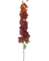 La flor artificial Delphinium 105 cm burdeos tiene un tallo único y largo con varias flores artificiales de color rojo oscuro y naranja y hojas verdes, aisladas sobre un fondo blanco.