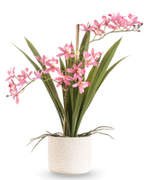 La Planta Artificial Mini Cymbidium Real Touch 45 cm rosa tiene largas hojas verdes y varios tallos florales de color rosa, dispuestos en una sencilla maceta de textura blanca y sobre un fondo liso.
