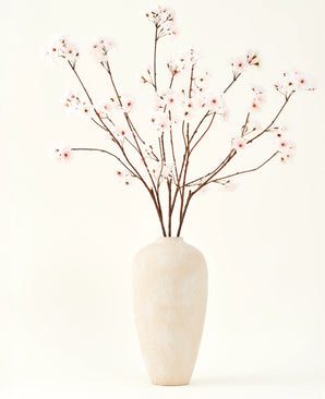 El ramo de flores artificiales Silk Cherry Blossom Blush de 114 cm tiene ramas altas y delicadas en un sencillo jarrón beige, que añade un toque suave y elegante a tu interior sobre un fondo liso y claro.