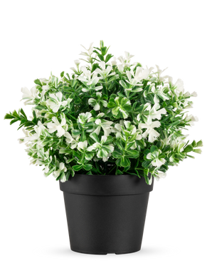 La Planta Artificial Trébol de Cuatro Hojas blanco UV 22 cm es una maceta negra con hojas verdes artificiales y pequeñas flores blancas sobre un fondo liso blanco.