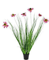 La Planta Césped Artificial Crisantemo 100 cm ignífugo es una planta en maceta con largas hojas verdes y largos tallos rematados con flores de color rosa brillante que parecen margaritas, sobre un fondo blanco.