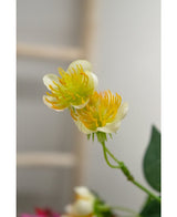 Primer plano de la flor artificial Ranúnculo de 77 cm en amarillo y blanco, con tallos y hojas verdes sobre un fondo difuminado, ideal para quien quiera crear un ramo con hermosas flores artificiales.