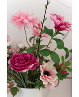 Un primer plano de la rosa Artificial Rose Real Touch de 56 cm, una rosa artificial rosa realista con hojas verdes, expuesta en un jarrón blanco sobre un fondo claro.
