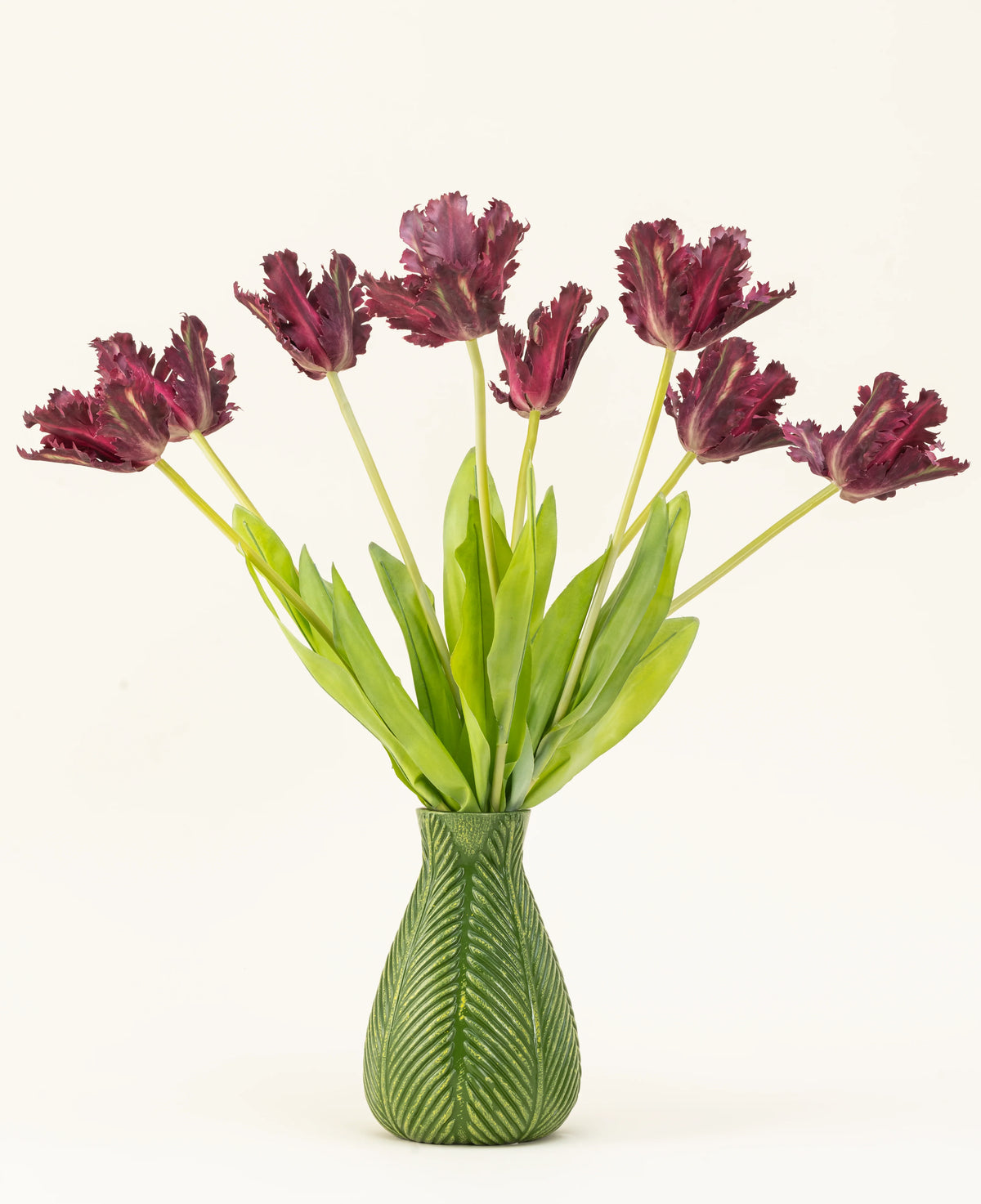 El ramo de flores artificiales de seda French Parakeet Tulip púrpura presenta tulipanes con flecos de color púrpura oscuro y largos tallos verdes en un jarrón con motivos de hojas verdes, creando una exhibición llamativa sobre un fondo blanco.