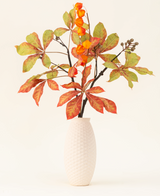 El ramo de flores artificiales de seda Autumn Flair tiene un jarrón con estructura blanca y rama tipo farol, flores naranjas en forma de farol y hojas verde-rojas, que forman un elegante decorado otoñal sobre un fondo liso y claro.