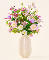Un jarrón de cerámica blanca contiene un colorido ramo de flores rosas, violetas y blancas de la colección 'Ramo de flores artificiales de seda Royal Bloom', acentuado con hojas verdes y presentado sobre un fondo liso y claro.