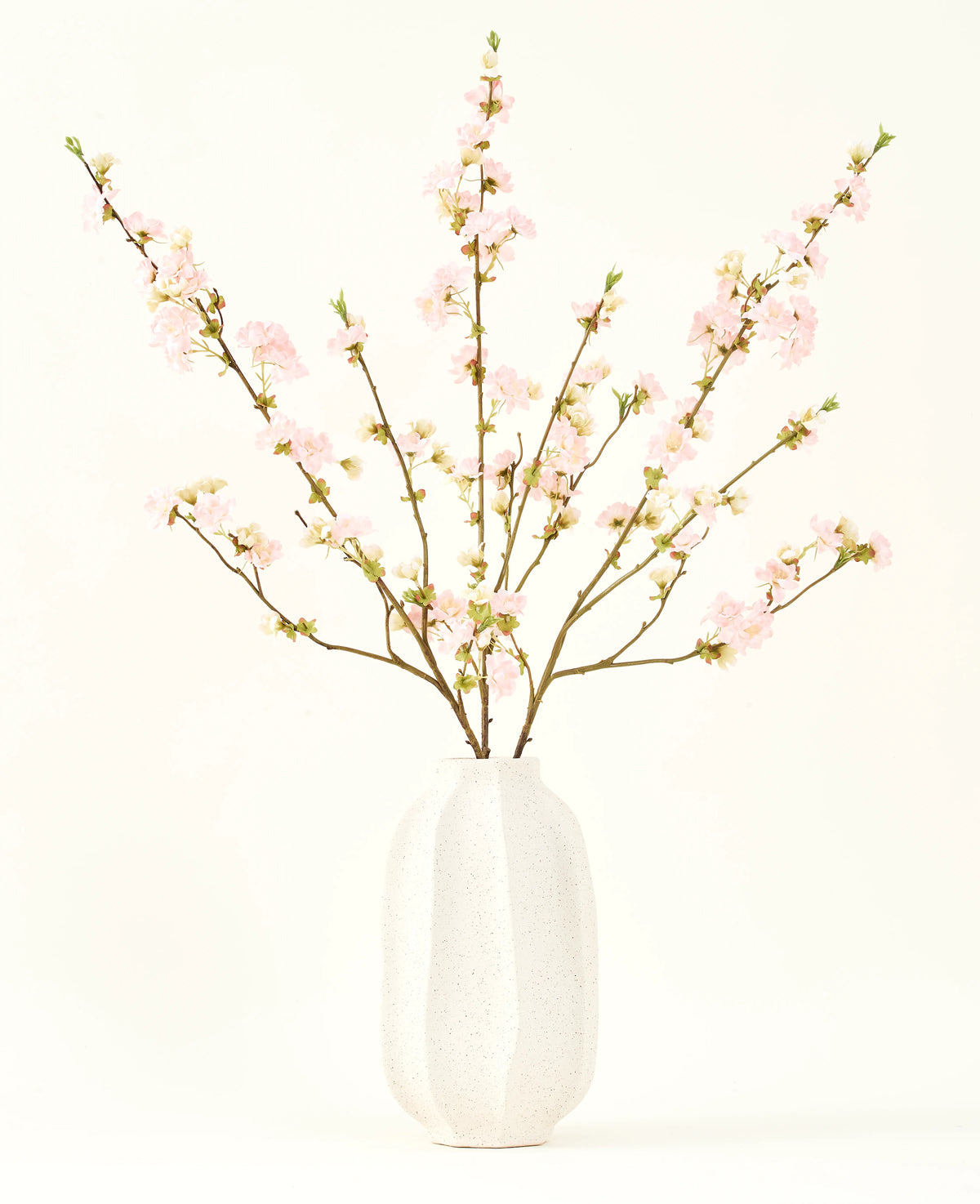 El ramo de flores artificiales de seda Flor de cerezo rosa claro de 94 cm presenta delicadas flores de cerezo artificiales de color rosa en un jarrón de cerámica blanca, que añade elegancia sobre un fondo claro y liso.
