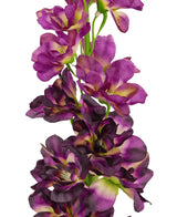 Een close-up van de Kunstbloem Delphinium Paars 79 cm, een hoge kunststengel met meerdere paarse en donkerpaarse bloemen met een groen en geel hart, tegen een witte achtergrond.