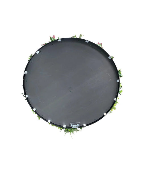 Un seto artificial sobre un trampolín de Ø100 cm con estructura negra, visto desde arriba con hojas verdes y flores rosas alrededor del borde, sobre un fondo blanco.