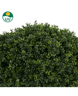 Un primer plano de la planta de boj artificial con tallo estilo romano UV 95 cm muestra hojas artificiales densas y de color verde brillante. Un símbolo de protección UV en la parte superior izquierda resalta la idoneidad para uso en exteriores.
