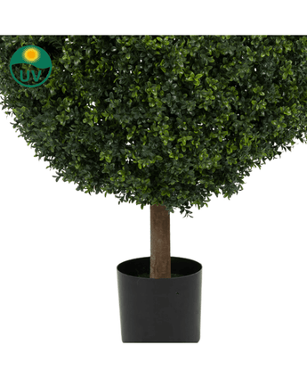 Un primer plano del boj artificial con tallo estilo romano UV 95 cm muestra densas hojas verdes y un tallo marrón en una maceta cilíndrica negra. En la esquina superior izquierda aparece un símbolo con protección UV con un sol y el texto "UV".