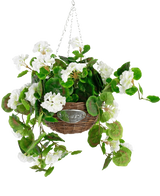 De Kunst begonia Wit in Mand UV 70cm heeft groene bladeren en witte begonia bloemen in een rieten mand met een metalen ketting, tegen een effen witte achtergrond.