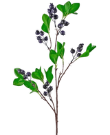 De Kunsttak Berry 76 cm paars heeft verschillende takken met groene ovale bladeren en trossen kleine, ronde, donkerpaarse bessen tegen een witte achtergrond.